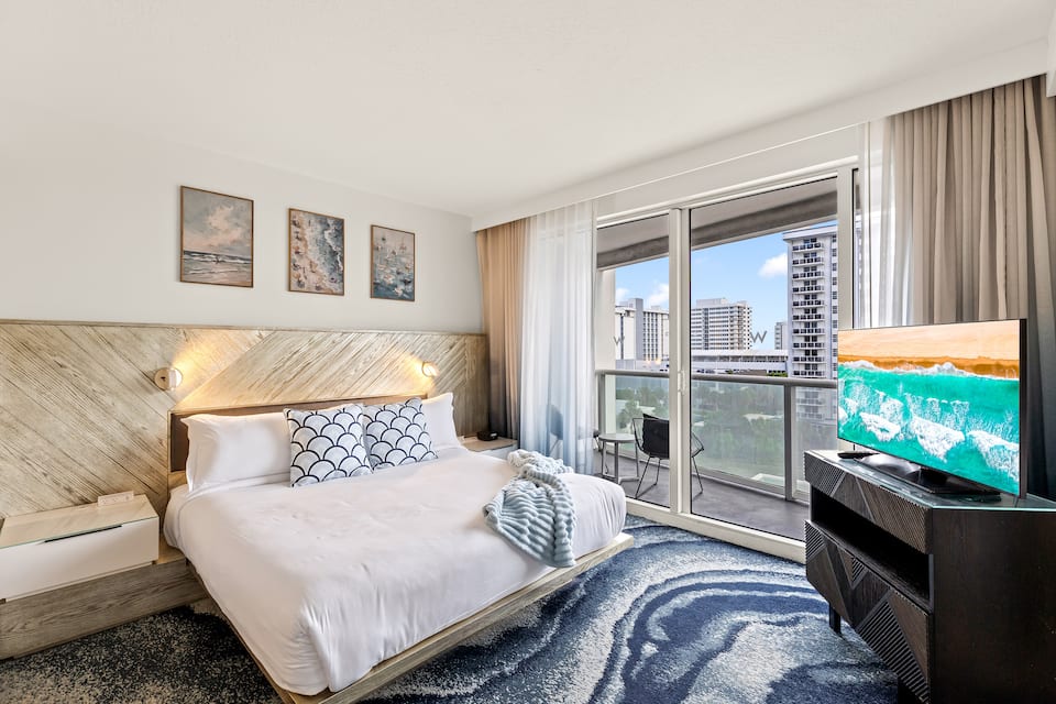 King bedroom with crisp white bedding and balcony doors