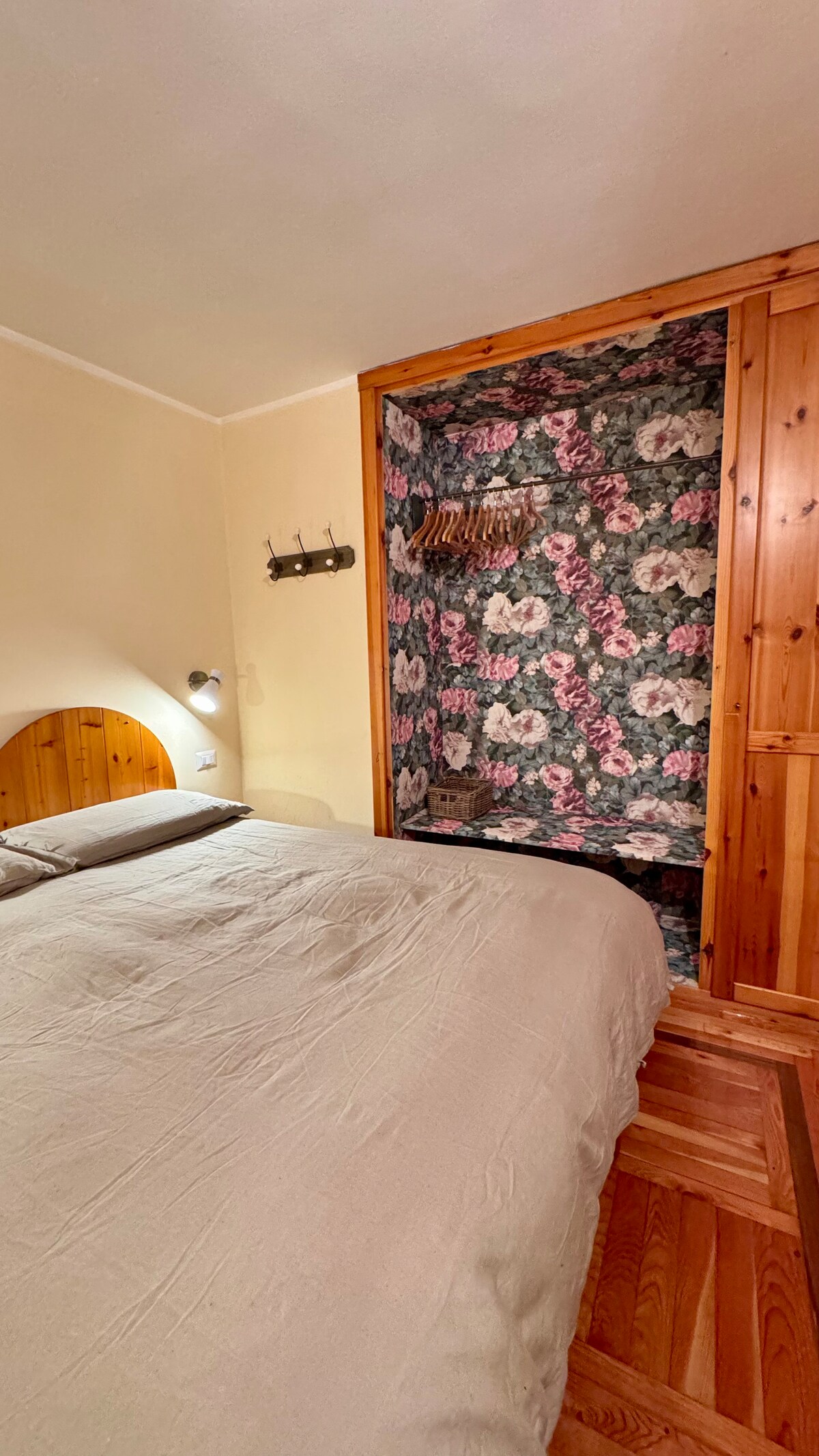 The master bedroom is small but functional, with a double bed in the center, an open closet to organize clothes, and a small TV located in front of the bed.