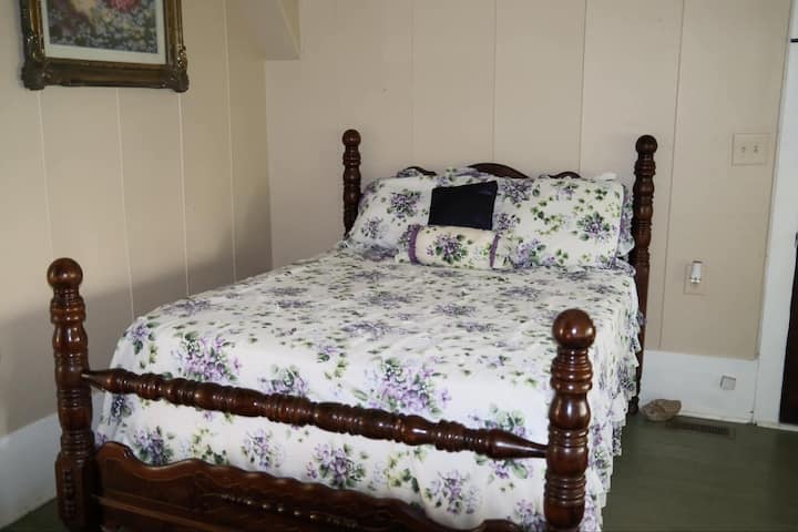 chumba cha kulala cha mbao cha kale kilichowekwa na madirisha mazuri ya ghuba. Chumba hiki kimetenganishwa na sebule na mapazia.