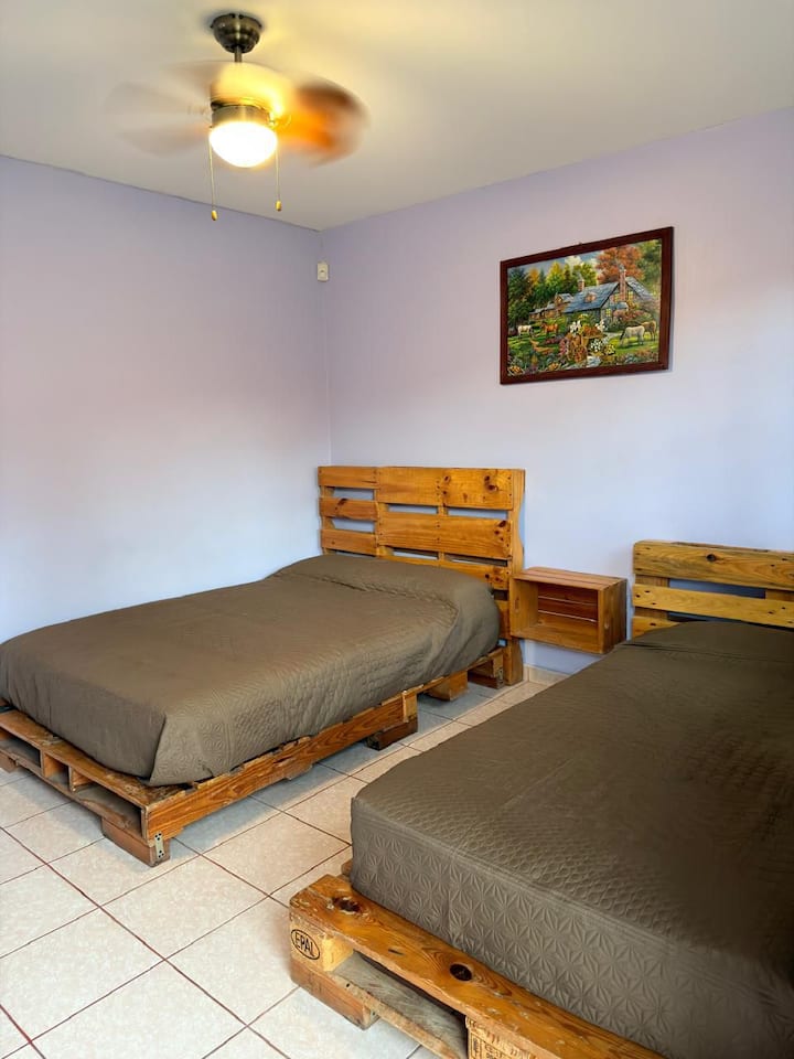 Cuenta con una cama matrimonial y una cama individual, ofreciendo versatilidad para sus invitados.

Equipada con un anaquel funcional que pueden utilizar como clóset y nuestro característico buró de caja de madera con estilo rústico.