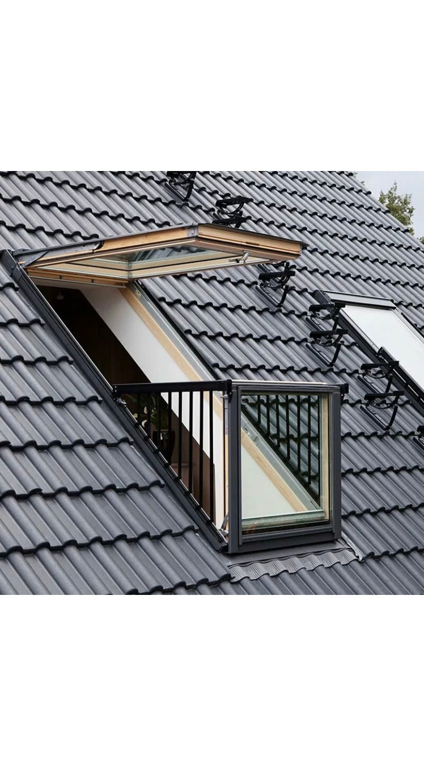 A modern skylight is showcased in an angular roof, featuring a wooden frame that opens outward. The structure is complemented by a glass railing, allowing for unobstructed views of the surroundings. Natural light floods the interior space below, enhancing the loft ambiance.