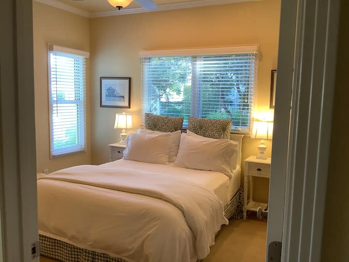 Dormitorio 1: habitación con vistas al jardín. Varias ventanas iluminan el espacio y persianas ajustables para la privacidad y para oscurecer. Cómoda cama tamaño queen con «colchón orgánico Monterey» y sábanas finas. Mesitas de noche con lámparas de lectura. Perfecto para dos personas o para un solo viajero.