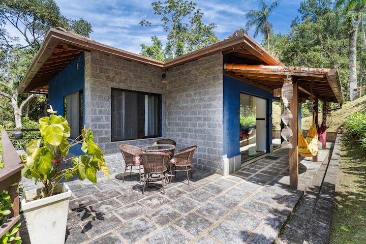 Kilátás az 1A ház bejáratára – Kültéri asztal, ahonnan élvezhető a kilátás a társasházra – Sárga függőágy az 1A ház vendége számára – Piros függőágy az 1B ház vendége számára