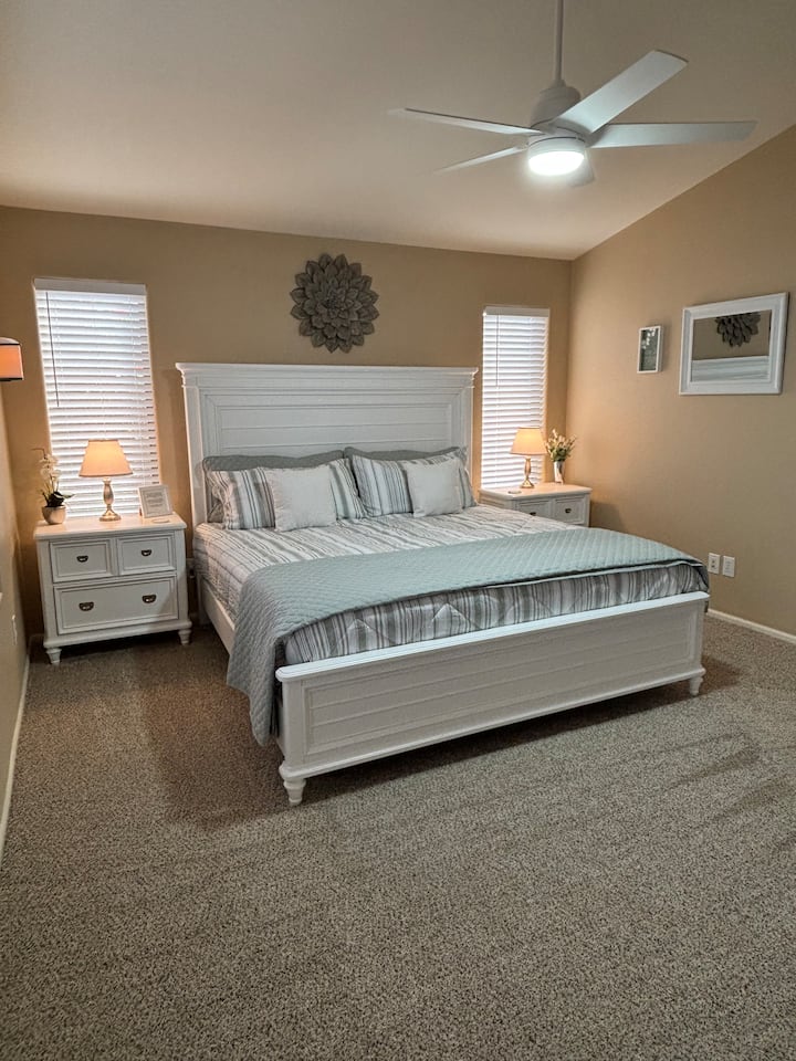 O quarto 1 tem uma cama king size com uma estrutura de cama ajustável, cômoda, mesas de cabeceira, ventilador de teto, TV e closet