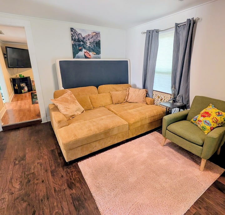 前门通往这个房间。 巨大的深色沙发。与标准双人床大小相同。 床垫垫加床单使这张床超级舒适！ （隐私性低）