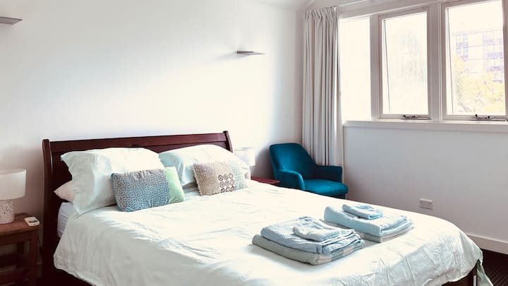 חדר שינה ראשי עם מיטת קווין סייז, המשקיף על הגינה. חדר רחצה צמוד. 