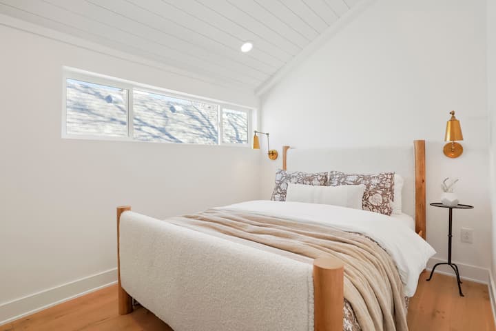 A stylish third bedroom awaits, boasting a comfortable queen-size bed, dresser, and TV.