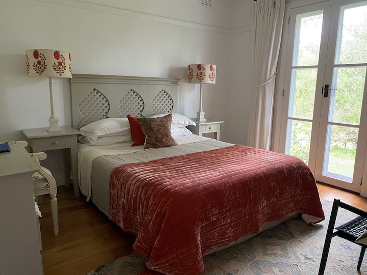 Queen bedroom with Smart HDTV, occasional seating and garden view.