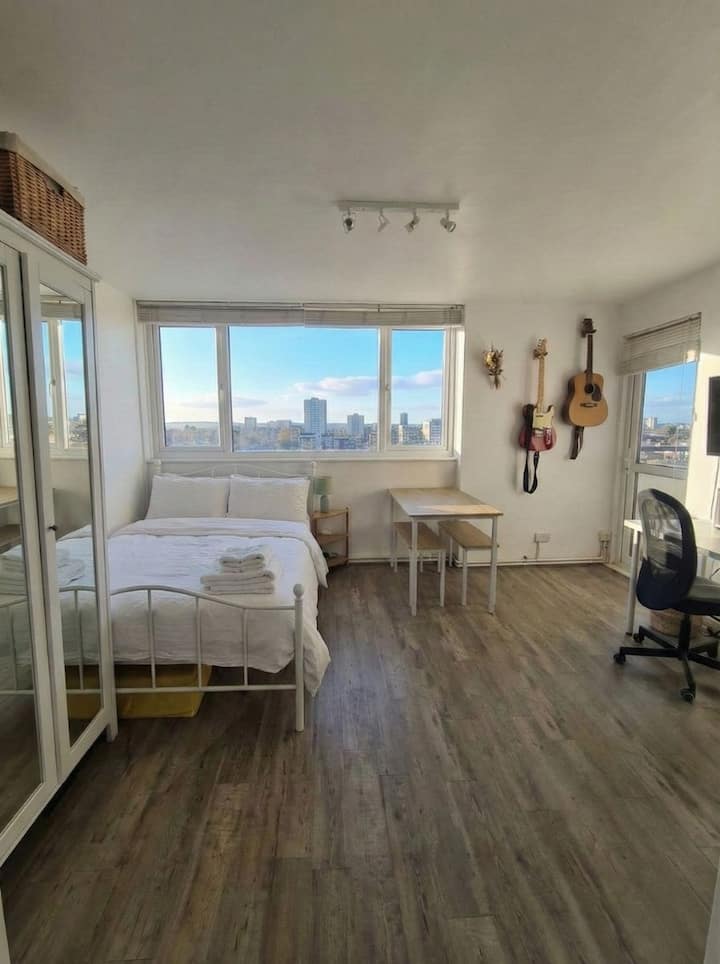 ห้องนอน/พื้นที่นั่งเล่นขนาดใหญ่และสว่างสวยงามพร้อมเตียงควีนไซส์ โต๊ะ 6 ที่นั่ง โต๊ะทำงานและเก้าอี้ และทีวี 
