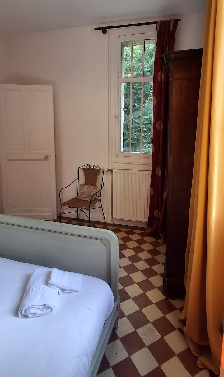 Située au RDC, en accès direct depuis la pièce de vie, la chambre n°1 dispose de deux fenêtres donnant sur le parc.
Le sol en damier rouge et crème est le sol historique de la maison. Une armoire napoleon III permet de ranger toutes vos affaires.