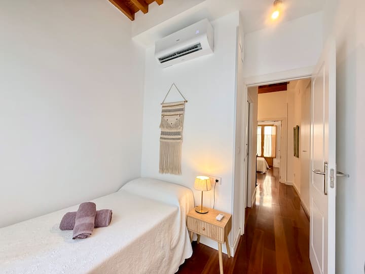Habitación individual minimalista y luminosa con aire acondicionado y detalles en madera cálida