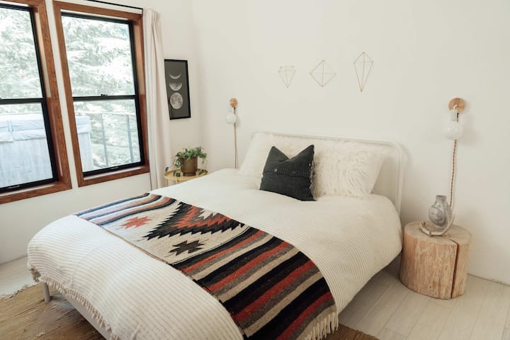One of two bedrooms on the main floor with queen bed, vaulted ceilings, and view of the deck.