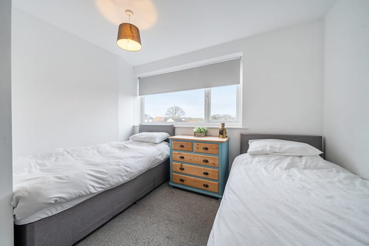 Spavaća soba s dva odvojena kreveta i komodom između njih.