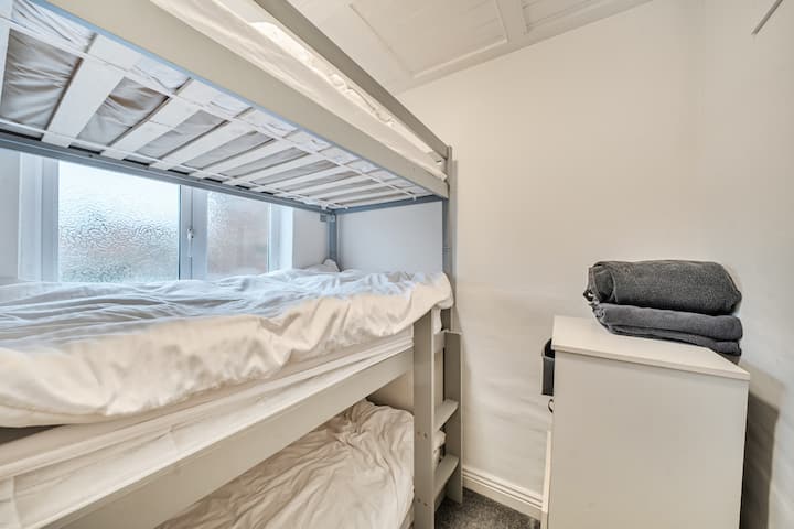 Krevet na kat ispod prozora sa složenim ručnicima na malom elementu.