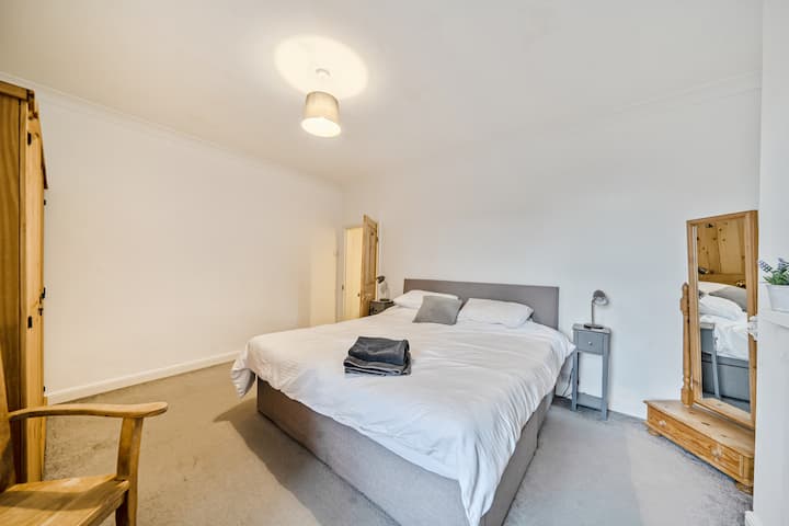 Dvokrevetna spavaća soba s noćnim ormarićima i složenim ručnicima na krevetu.