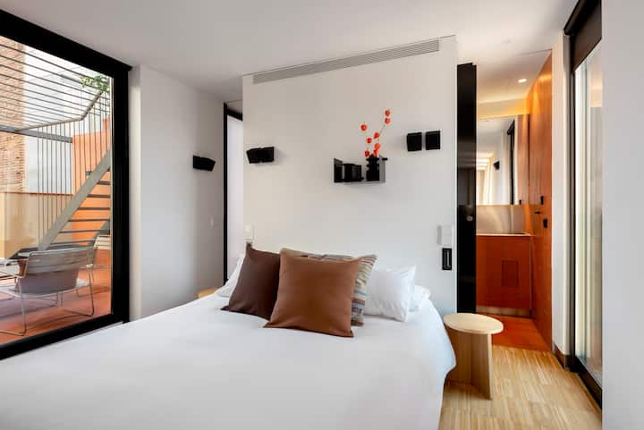 Chumba kikuu cha kulala chenye kitanda aina ya queen na bafu la ndani, mwonekano wa mlima wa Montjuic na mojawapo ya matuta
