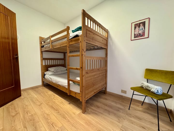 Spavaća soba s drvenim krevetom na kat, savršena za djecu ili prijatelje na odmoru. Funkcionalan i udoban prostor s parketom i toplom i jednostavnom atmosferom u alpskom stilu.