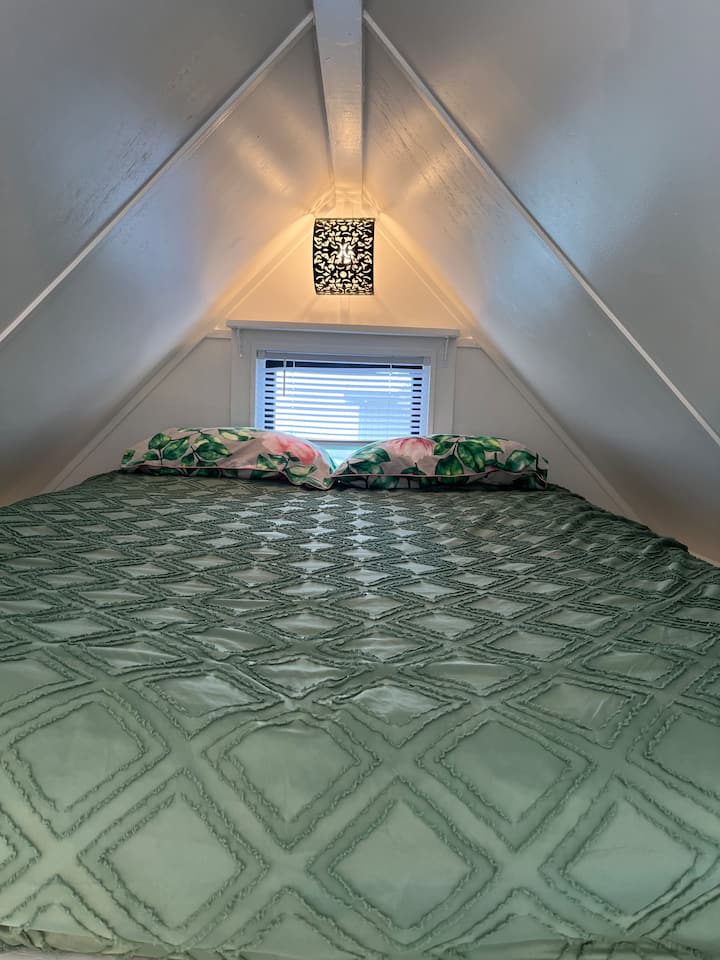 This is the loft sleeping space with Queen size floor mattress access is by ladder, window and amazing views, small shelf, lighting and plug socket for phones.