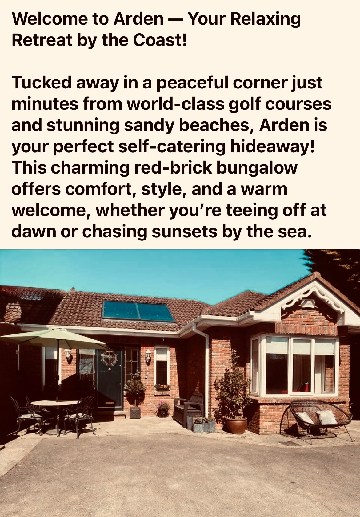 The red-brick bungalow is featured in a tranquil setting, showcasing a welcoming entrance with a covered porch. Lush greenery surrounds the property, enhancing its appeal. The well-maintained facade and windows reflect a charming style suitable for relaxation near the coast.