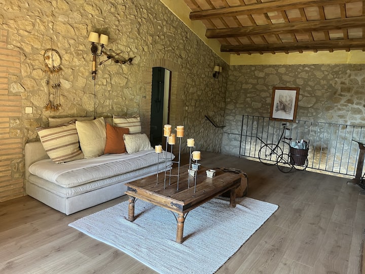 Upper-floor living area with stone walls and exposed-beam ceiling. A spacious and peaceful corner that retains the rustic character of the house and provides the perfect place to unwind.