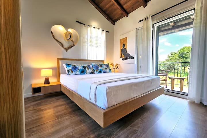 Tweepersoonskamer op de bovenste verdieping die direct uitkomt op een eigen gemeubileerd balkon met uitzicht op het bos.