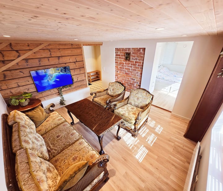 (ב) חלק נפרד מהבית עם חדר שינה פרטי לשני אנשים, חדר רחצה ומטבח.  
טרקלין נעים עם ריהוט וינטג', מושלם למנוחה, קריאה או שיחה שקטה.