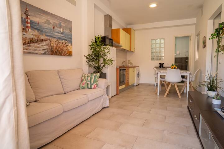 Salón-cocina diáfano con sofá y salida a la terraza: espacio abierto y muy luminoso.