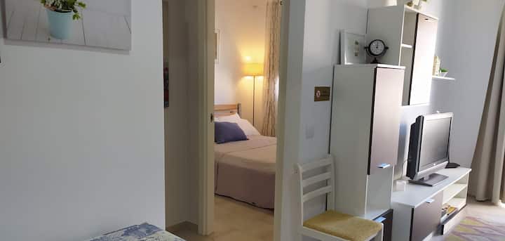 Rincón del dormitorio con TV y armario: espacio cómodo y bien aprovechado.