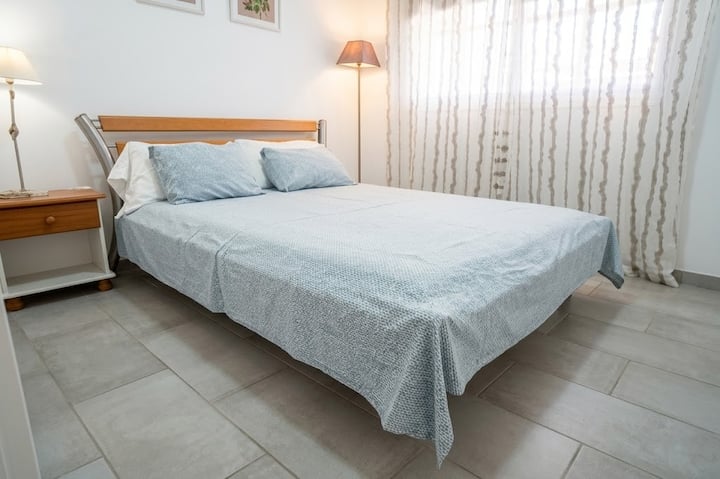 Dormitorio con cama de matrimonio y ropa de cama en azul: descanso tranquilo y luminoso.