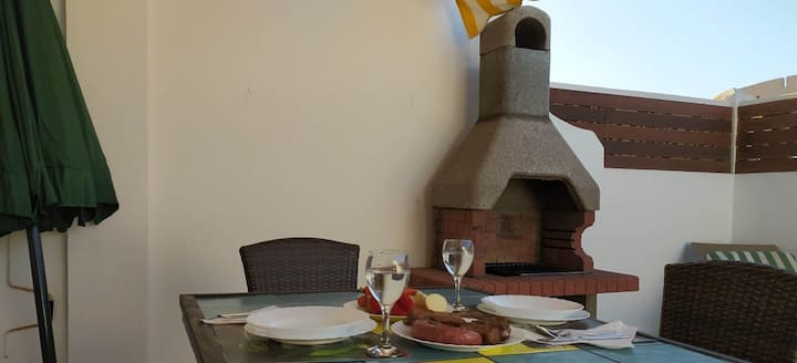 Terraza con barbacoa y mesa vestida: perfecta para una parrillada al aire libre.