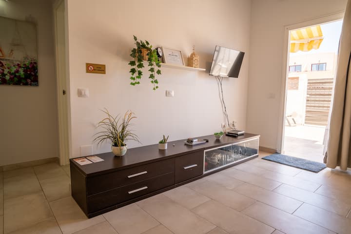 Salón con mueble de TV y salida a la terraza con toldo: cómodo y lleno de luz natural.