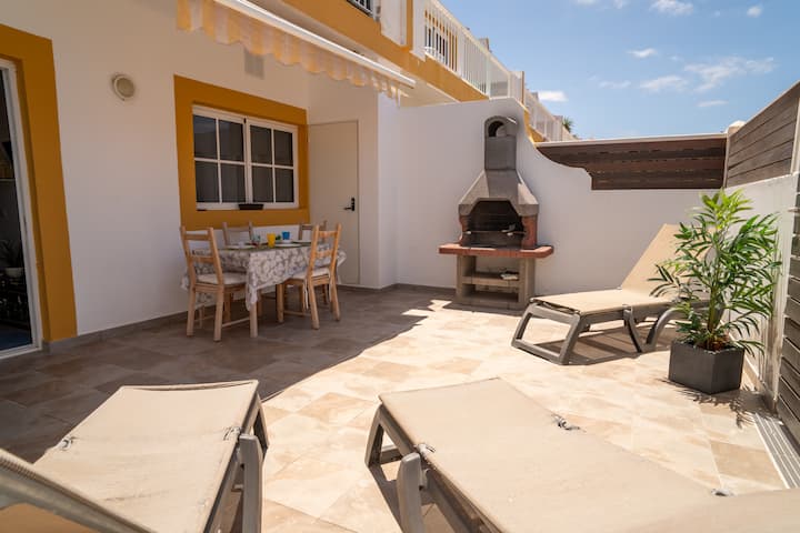 Terraza con comedor, barbacoa y tumbona: espacio exterior soleado para disfrutar.