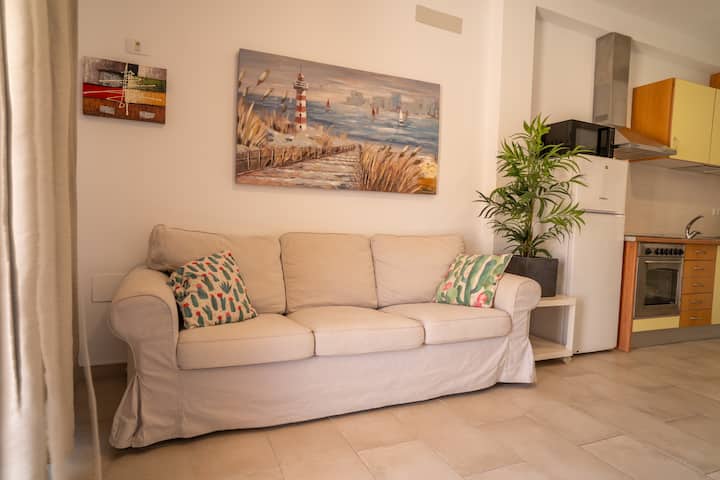 Sofá amplio con cojines de colores y cuadro marinero: rincón alegre para relajarse.
