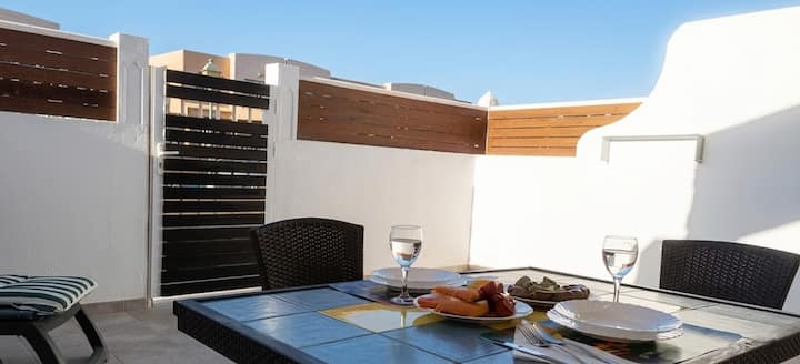 Mesa exterior con vajilla y copas en la terraza: lista para una comida al aire libre.