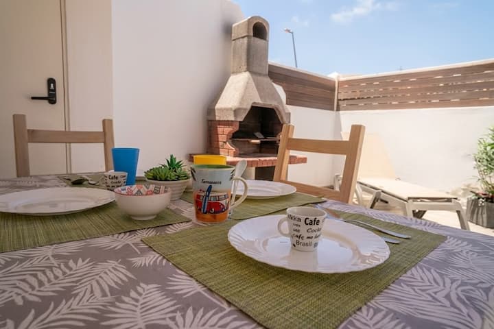 Detalle de la mesa de la terraza junto a la barbacoa: comidas al sol con todo a mano.