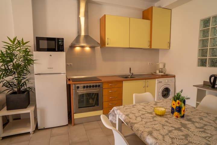 Comedor abierto a la cocina con mesa y campana: espacio práctico y muy luminoso.