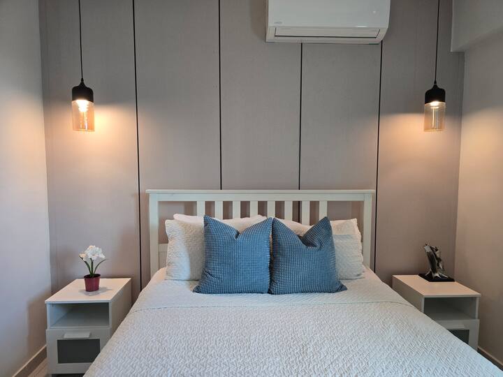 Habitación con cama matrimonial, aire acondicionado, lamparas y tv 50 pulgadas.
