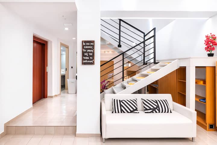 Pasillo en el nivel inferior con un sofá incorporado debajo de la escalera, que conecta el dormitorio del sótano y la sala de juegos: una zona luminosa y práctica para dejar las bolsas y relajarse un momento.
