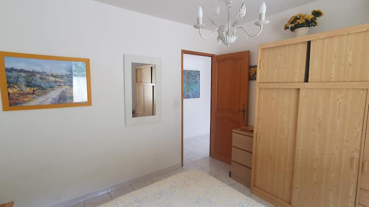 The Provence room with a large closet and a dresser. From the room, there is a door leading to a long hallway, as well as a toilet and bathroom.