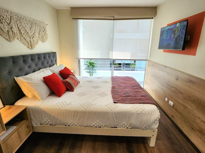 Dormitorio amplio y acogedor con cama Queen de gran confort, ropa de cama suave y detalles modernos. Ideal para descansar plenamente después de un día de trabajo o exploración. Cuenta con rollers para mantener tu privacidad y cortinas oscuras. 