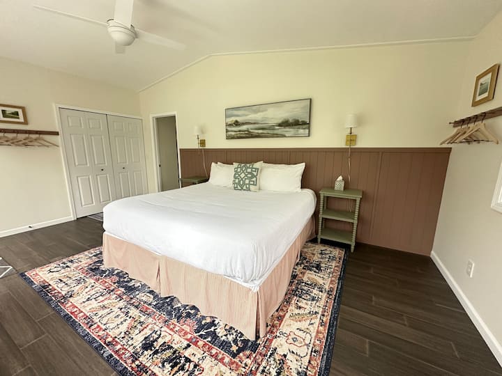 Bedroom 4 has a king bed, ensuite half bathroom, desk, and sliding doors which open to a private deck.