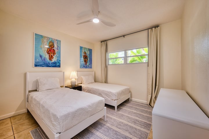 Bright twin bedroom with coastal art, soft light, and a peaceful feel