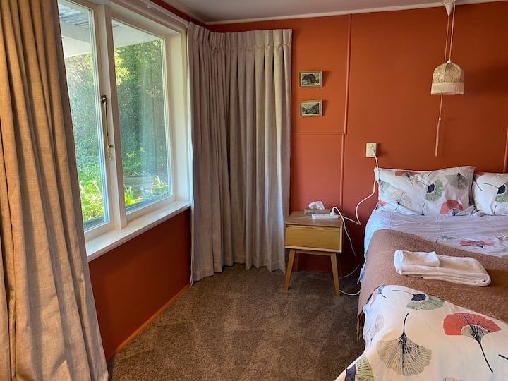 Cama tamaño queen, abajo en la habitación Pōhutukawa (llamada así por las paredes rojas).