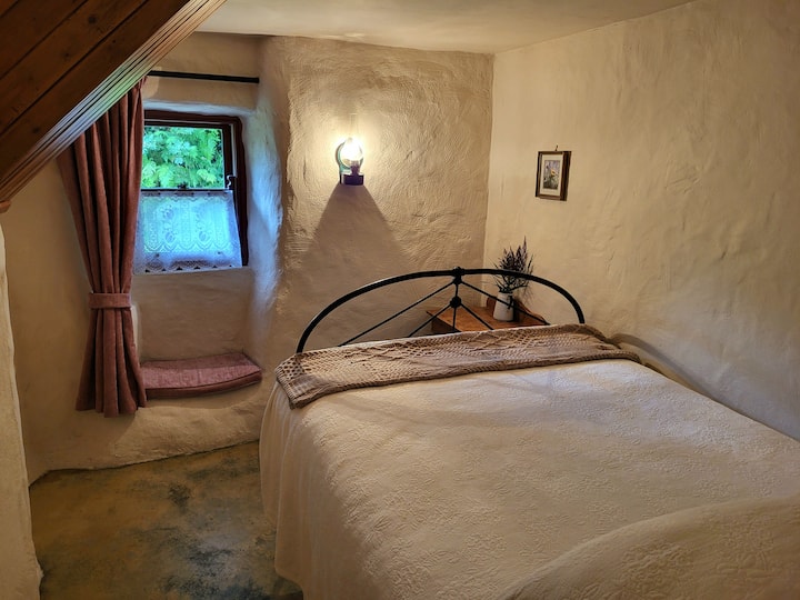 Bedroom One: Traditional iron-framed bed (Double) with white cotton bedspread, and an ensuite bathroom 