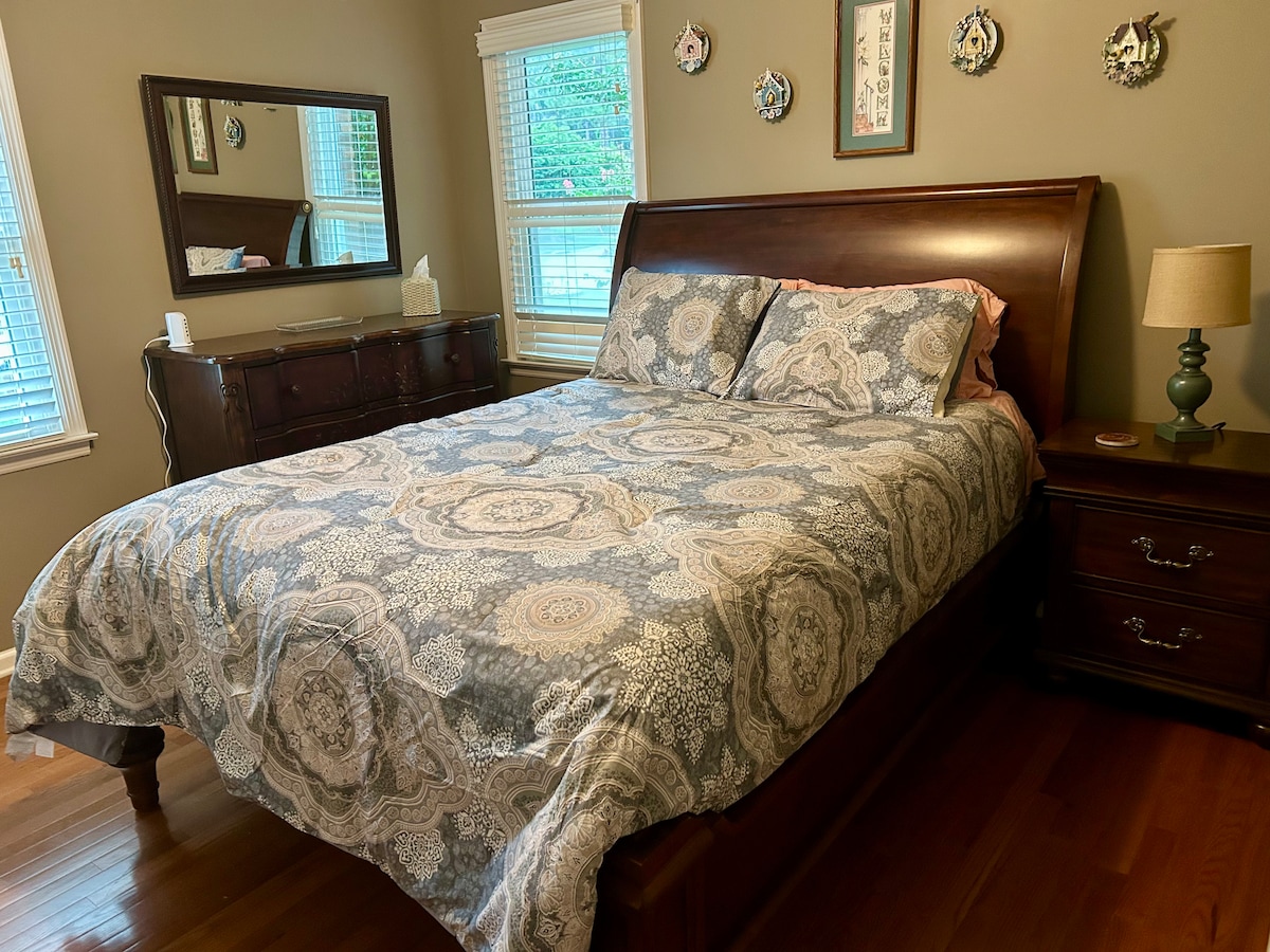 Slaapkamer met queensize bed, dressoir, nachtkastje en kast. 