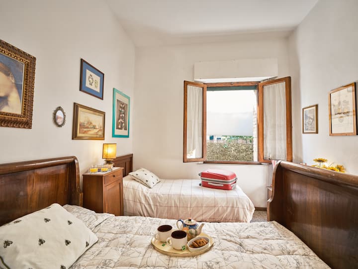 Bright and welcoming twin room with classic wooden beds, warm decor, and a large window that fills the space with natural light.