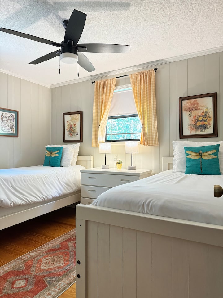Second bedroom has two twin beds, ceiling fan, dresser, closet, and view of the front yard