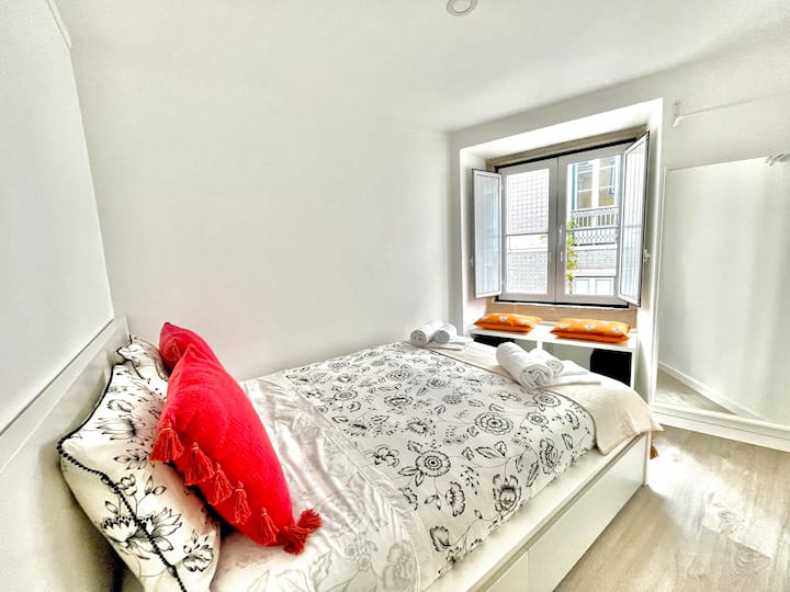 Chambre lumineuse avec lit double, miroir et vue sur la fenêtre