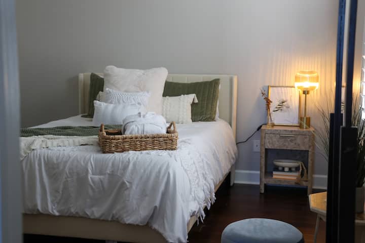 Cama tamaño queen con cubrecolchón y muchas mantas y almohadas adicionales