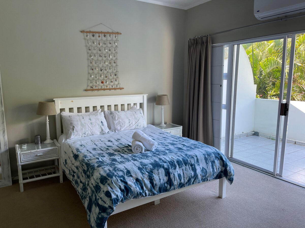 楼上的主卧配有一张标准双人床，套房配有浴缸、马桶和洗脸盆、两套橱柜和一扇通往阳台的滑动门。 